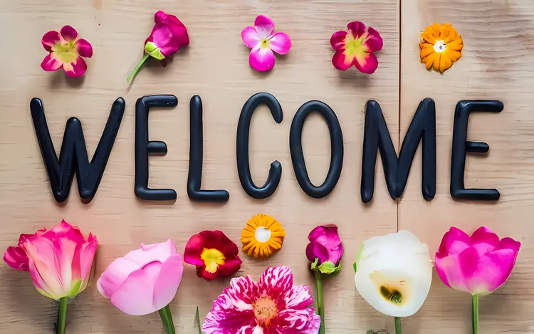 Welcome Text with Flowers on Wooden Background