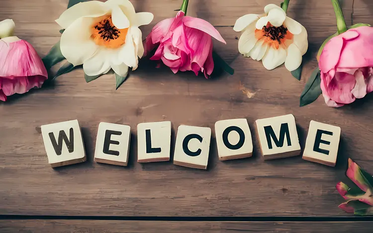 Welcome Sign with Flowers on Wooden Background