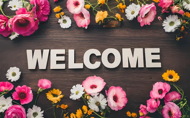 Welcome Text with Flowers on Wooden Background